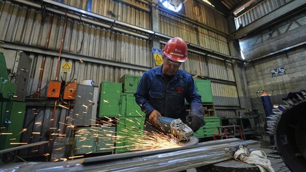 Un trabajador lija metal en una planta que produce piezas para vehículos eléctricos grandes en la Ciudad de México Un trabajador lija metal en una planta que produce piezas para vehículos eléctricos grandes en la Ciudad de México - Sputnik Mundo