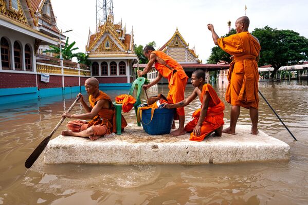 Monjes tailandeses navegan por el recinto inundado del templo Wat Kai Tia utilizando una gran lámina de espuma de poliestireno a modo de balsa. - Sputnik Mundo
