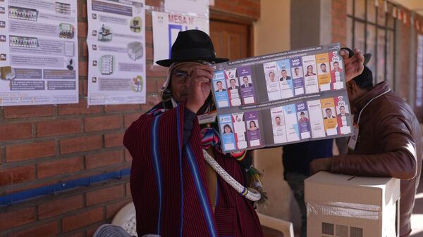 Un funcionario electoral muestra a los votantes la papeleta presidencial durante las elecciones generales en Jesús de Machaca, Bolivia, el domingo 17 de agosto de 2025. (Foto AP/Juan Karita) - Sputnik Mundo