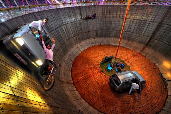 Los especialistas Babar Jan y Ajim Jan actúan con una bicicleta y un automóvil en el Pozo de la Muerte, conocido localmente como Maut ka kuaan, en el recinto ferial de Mela, India. Este pozo o cuenco, también conocido como muro de la muerte, tiene unos 9 metros de profundidad y está hecho de tablones de madera, sostenidos desde el exterior. - Sputnik Mundo