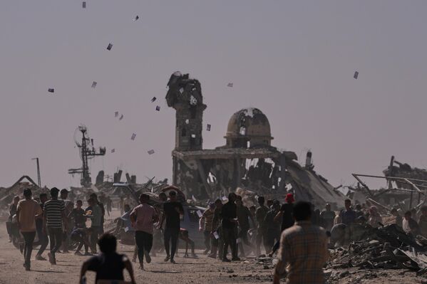 Palestinos recogen folletos lanzados por un dron israelí, advirtiéndoles que se mantengan alejados de la llamada Línea Amarilla, en la ciudad de Jan Yunis, en el sur de la Franja de Gaza. - Sputnik Mundo