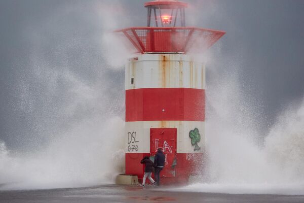 La gente se mantiene cautelosa mientras las olas chocan contra un muelle durante la tormenta Benjamín en La Haya, Países Bajos. El Real Instituto Meteorológico de los Países Bajos emitió una alerta meteorológica naranja para las provincias costeras occidentales, con ráfagas de viento de hasta 120 kilómetros por hora. - Sputnik Mundo
