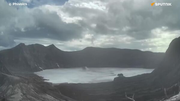 Una columna de ceniza contra un arco iris: el volcán activo más pequeño del planeta entra en erupción en Filipinas - Sputnik Mundo