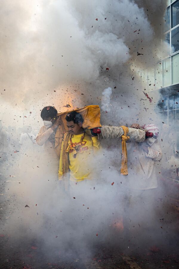Devotos lanzan petardos durante una procesión callejera desde el santuario Jui Tui en la ciudad de Phuket, en el marco del Festival Vegetariano de Phuket en  Tailandia.  En el festival, los devotos siguen una dieta vegetariana estricta en honor a los Nueve Dioses Emperadores. Se celebra este año su bicentenario y sigue siendo uno de los eventos religiosos más populares de Tailandia. - Sputnik Mundo