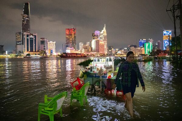 Una mujer camina junto al río Saigón mientras el nivel del agua alcanza su máximo anual, en la Ciudad Ho Chi Minh, Vietnam. Ho Chi Minh es una de las ciudades costeras que se hunden más rápidamente en el mundo y ha sufrido inundaciones cada vez más graves debido al cambio climático, el aumento del nivel del mar y la rápida urbanización. - Sputnik Mundo