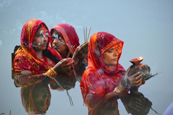 Mujeres hindúes rinden culto al dios del Sol en un estanque de Calcuta, durante la madrugada del festival religioso de Chhath Puja, en la India. - Sputnik Mundo
