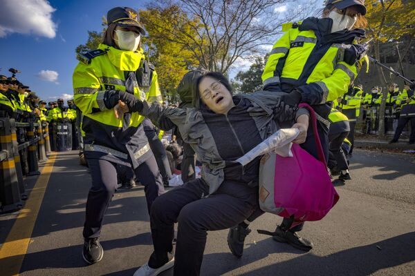 Agentes de Policía detienen a un manifestante que protestaba contra Donald Trump frente al Museo Nacional de Gyeongju, donde el mandatario de EEUU se reunió con su homólogo surcoreano, Lee Jae-myung, durante la cumbre de la APEC. - Sputnik Mundo