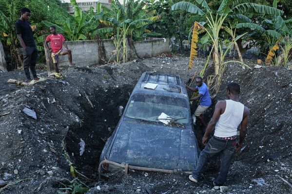 Intento de recuperar un automóvil parcialmente sepultado por la tierra tras el huracán Melissa en Haití. - Sputnik Mundo