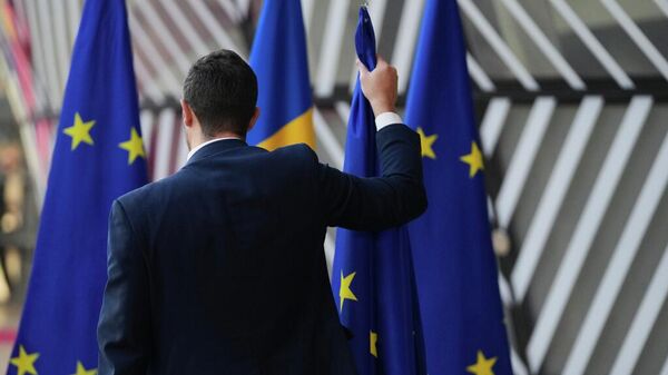 Una persona retira las banderas de la Unión Europea en Bruselas - Sputnik Mundo