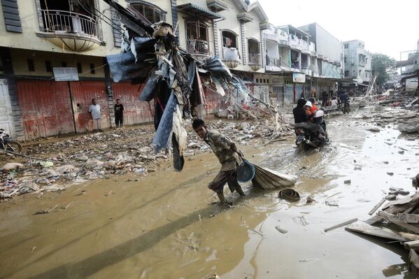 Un sobreviviente arrastra una bolsa con pertenencias rescatadas a través del barro en una zona afectada por las inundaciones repentinas en la isla de Sumatra, Indonesia.  - Sputnik Mundo
