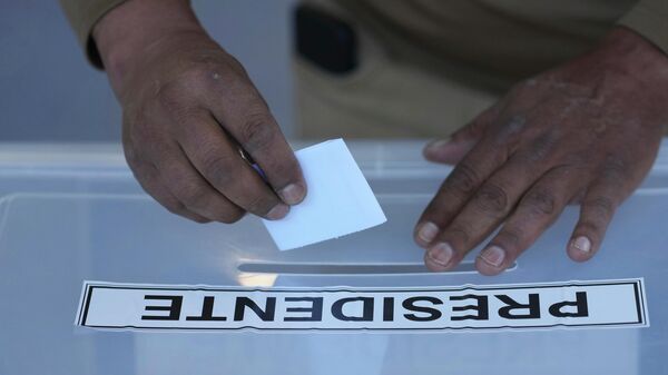 Una persona vota durante las elecciones generales en Santiago, Chile. - Sputnik Mundo