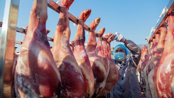 Un empleado cuelga jamones para secarlos en una fábrica de alimentos el 1 de diciembre de 2023 en Jinhua, provincia de Zhejiang, China  - Sputnik Mundo
