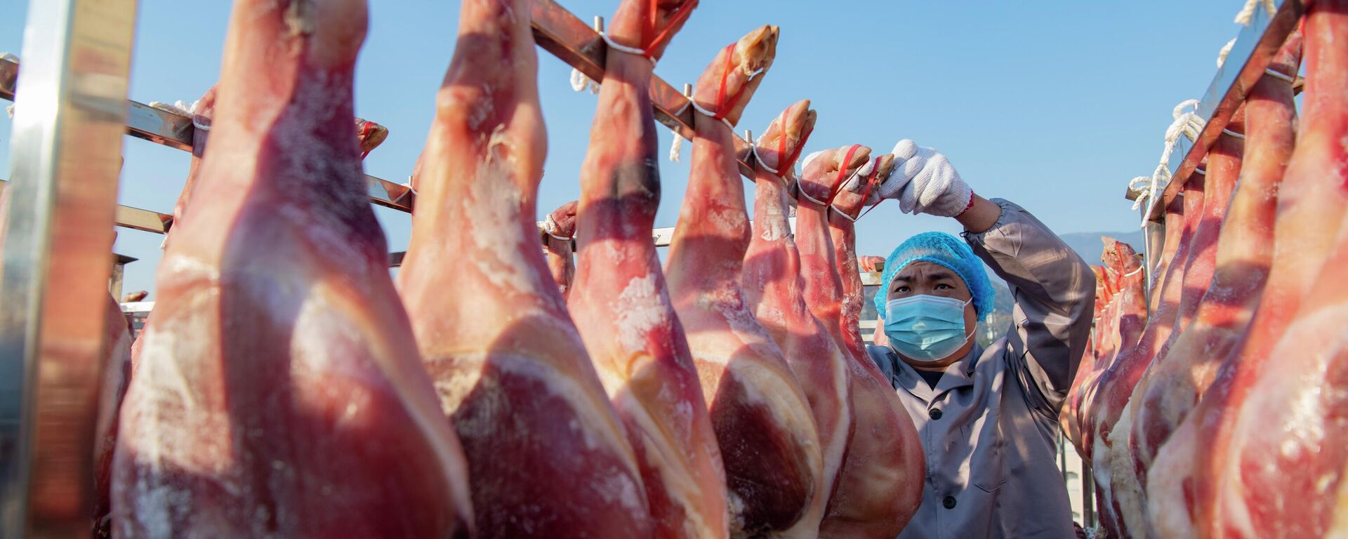 Un empleado cuelga jamones para secarlos en una fábrica de alimentos el 1 de diciembre de 2023 en Jinhua, provincia de Zhejiang, China  - Sputnik Mundo, 1920, 18.12.2025