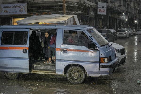 Una familia palestina viaja en un automóvil bajo la lluvia en la ciudad de Gaza. - Sputnik Mundo
