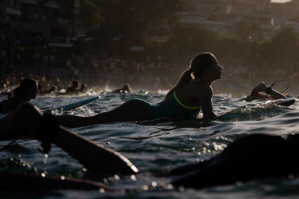 Cientos de personas participan en una remada y natación durante el amanecer en Bondi Beach, para honrar a las víctimas del tiroteo ocurrido allí, en Sídney, Australia. - Sputnik Mundo
