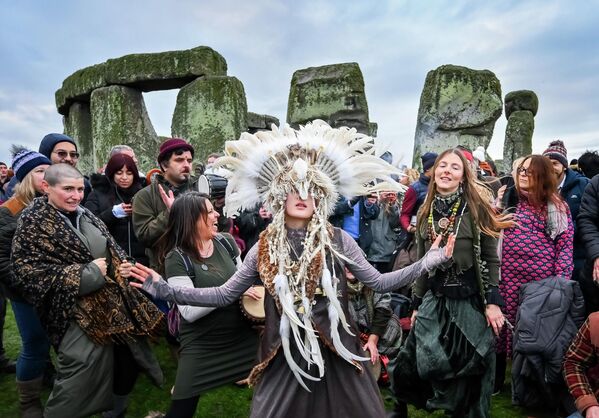 Kefan Wang, un chamán de China, y Abbie Coombs, de Londres, bailan mientras la gente celebra el amanecer del solsticio de invierno en Stonehenge, el célebre monumento prehistórico situado en la llanura de Salisbury, en el Reino Unido. - Sputnik Mundo