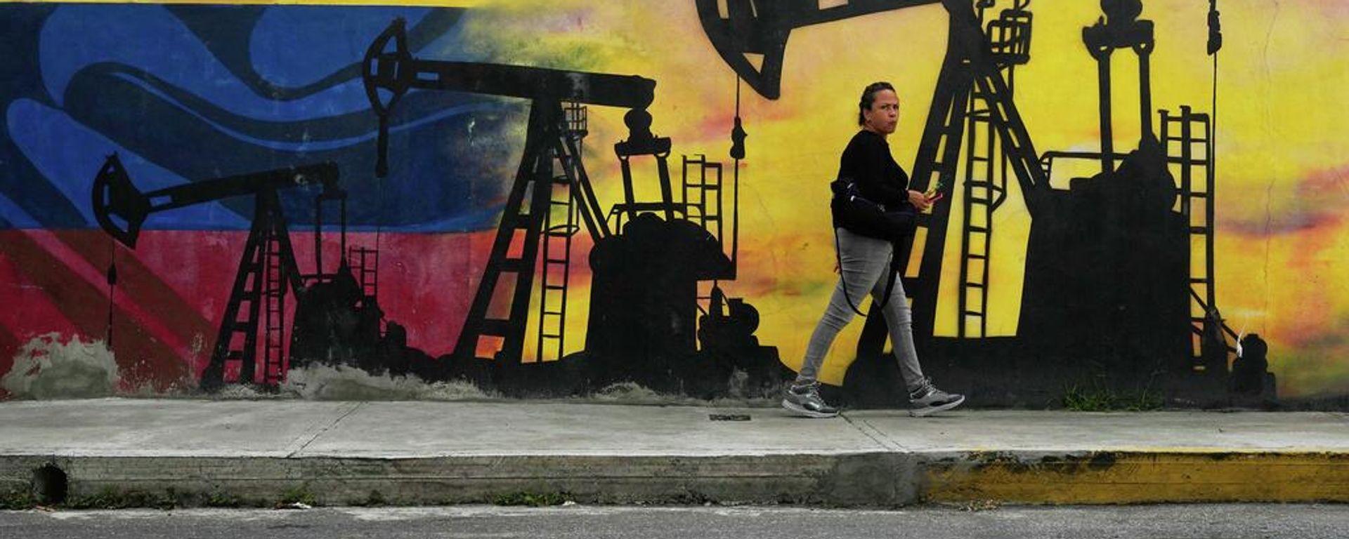 Un lugareño pasa junto a un mural que representa bombas de petróleo y pozos en Caracas - Sputnik Mundo, 1920, 03.09.2026