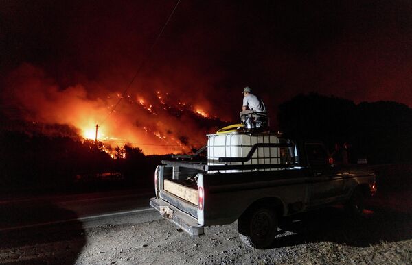 Un hombre observando un incendio forestal desde su automóvil en Cerro Pirque, en la provincia argentina de Chubut. - Sputnik Mundo