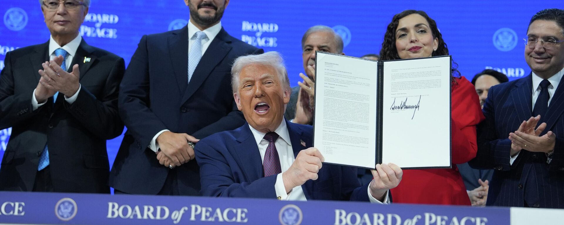El presidente Donald Trump, en el centro, sostiene una carta firmada de la Carta del Consejo de Paz durante la Reunión Anual del Foro Económico Mundial en Davos, Suiza - Sputnik Mundo, 1920, 22.01.2026