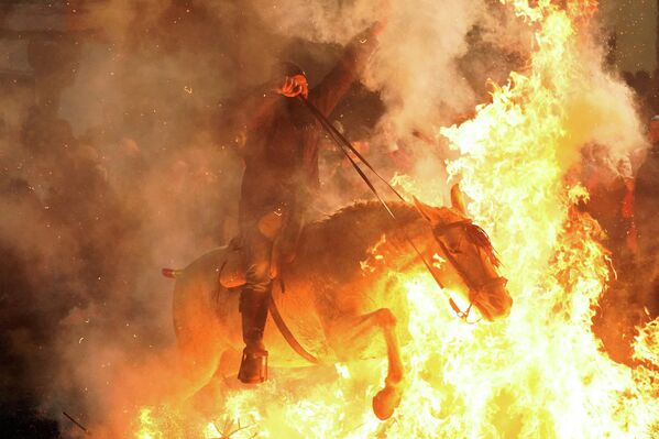 Un jinete cruza una hoguera durante la fiesta anual de las Luminarias, celebrada la víspera del día de San Antonio —patrón de los animales en España— en la localidad de San Bartolomé de Pinares. - Sputnik Mundo