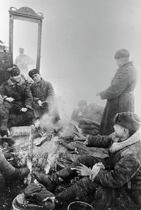 "Primero, bloquearemos Leningrado (herméticamente) y destruiremos la ciudad (...) En primavera, penetraremos en la ciudad (...) nos llevaremos a todos los que queden con vida al interior de Rusia o los haremos prisioneros, arrasaremos Leningrado por completo", se lee en la Enciclopedia Militar Soviética, refiriéndose a las palabras de Hitler.En la foto: artilleros descansan junto a una hoguera, al lado de un tocador con espejo trumeau: lo único que milagrosamente sobrevivió en la aldea que los invasores nazis entregaron al fuego y a la espada. - Sputnik Mundo