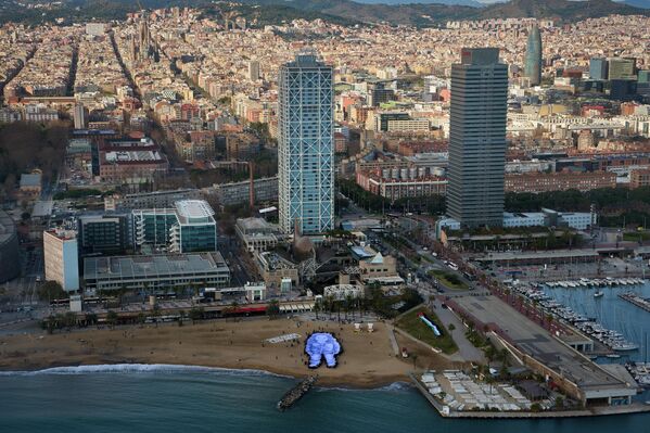 Un grupo de personas sostiene un gran retrato de Hind Rajab —una menor palestina de cinco años que falleció durante el conflicto en la Franja de Gaza— en una playa de la ciudad española de Barcelona. - Sputnik Mundo