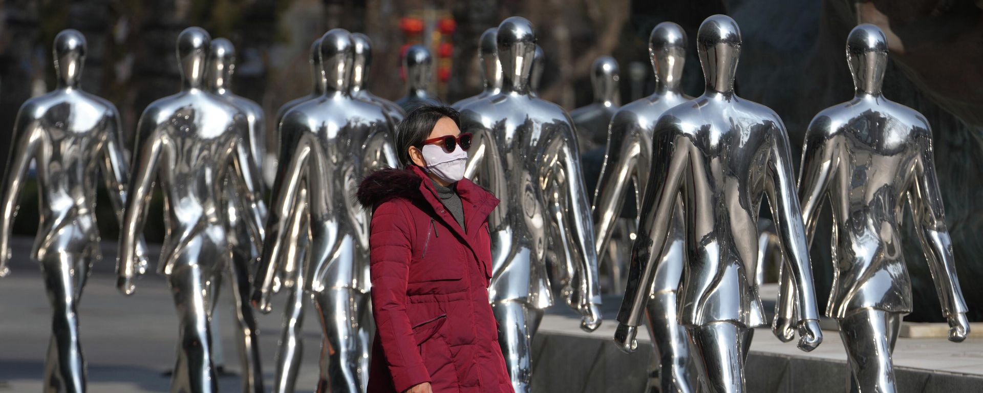 Una mujer pasa caminando junto a esculturas de personas exhibidas frente a un centro comercial en Pekín, China. - Sputnik Mundo, 1920, 27.06.2026