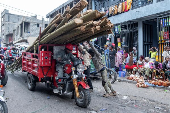 Una persona transporta troncos en un mercado, República Democrática del Congo. - Sputnik Mundo