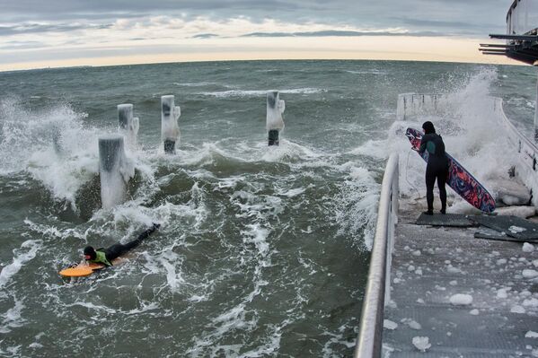 Los surfistas actúan en el frío mar Báltico desde el muelle helado de la playa de Timmendorfer Strand, en Alemania.  - Sputnik Mundo