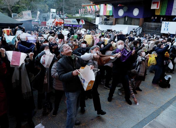 Los visitantes intentan atrapar frijoles con sus bolsas durante la ceremonia anual de dispersión de frijoles Setsubun, para celebrar la llegada de la primavera y alejar a los malos espíritus en el templo Takahata Fudoson Kongoji en Tokio, Japón. - Sputnik Mundo