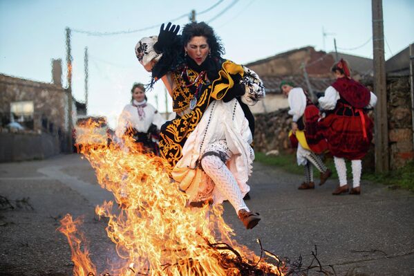 Una mujer vestida con un traje típico regional salta una hoguera durante el salto del piorno de las fiestas de Las Águedas, en Andavías, Castilla y León, España.  Esta celebración, también conocida como el Día de las Mujeres, es una tradición muy arraigada en Castilla y León, especialmente en las zonas rurales. Se celebra durante siete días, durante los cuales los asistentes bailan, comen, cantan e incluso saltan una hoguera. - Sputnik Mundo