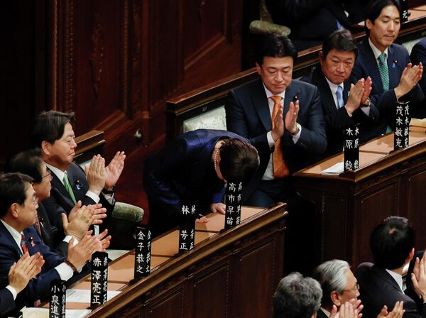 La primera ministra japonesa, Sanae Takaichi, hace una reverencia mientras recibe aplausos tras ser reelegida en su cargo, en la Cámara Baja del Parlamento en Tokio. - Sputnik Mundo