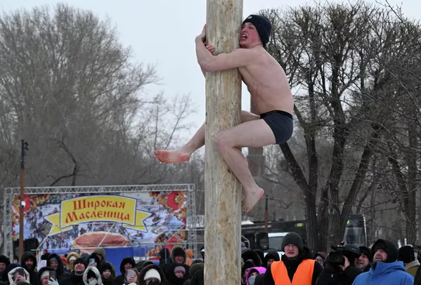 È tradizione celebrare la Maslenitsa con festeggiamenti sfarzosi. In passato, l'inverno veniva salutato con canti popolari, danze in cerchio e giochi, come combattimenti corpo a corpo, gite in slitta, gare di blini e la tradizionale e impegnativa gara di arrampicata su palo. Un palo di legno liscio, alto tra gli 8 e i 15 metri, spesso ricoperto di ghiaccio, viene eretto al centro della piazza cittadina e in cima vengono posti dei premi: stivali, vestiti, un samovar, denaro o persino un gallo vivo. I partecipanti tentano di arrampicarsi, dimostrando forza e abilità. Nella foto: un uomo si arrampica sul palo per raggiungere il premio. È tradizione celebrare la Maslenitsa con festeggiamenti sfarzosi. In passato, l'inverno veniva salutato con canti popolari, danze in cerchio e giochi come la lotta, le gite in slitta, le gare di blini e la tradizionale e impegnativa gara di arrampicata su un palo. Un palo di legno liscio, alto tra gli 8 e i 15 metri, spesso ricoperto di ghiaccio, viene eretto al centro della piazza e in cima vengono posti premi come stivali, vestiti, un samovar, denaro o persino un gallo vivo. I partecipanti tentano di arrampicarsi, dimostrando forza e abilità. Nella foto: un uomo si arrampica sul palo per raggiungere il premio. - Sputnik Mundo