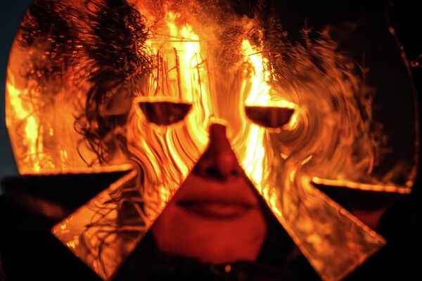 Las grandes hogueras también eran una tradición importante. Se encendían para derretir la nieve restante y acelerar la llegada de la primavera. En ellas se arrojaban objetos viejos e innecesarios, como forma de desprenderse de lo que impedía avanzar.En la foto: una joven con máscara observa la efigie en llamas. Las grandes hogueras también eran una tradición importante. Se encendían para derretir la nieve restante y acelerar la llegada de la primavera. En ellas se arrojaban objetos viejos e innecesarios, como forma de desprenderse de lo que impedía avanzar.En la foto: una joven con máscara observa la efigie en llamas. - Sputnik Mundo