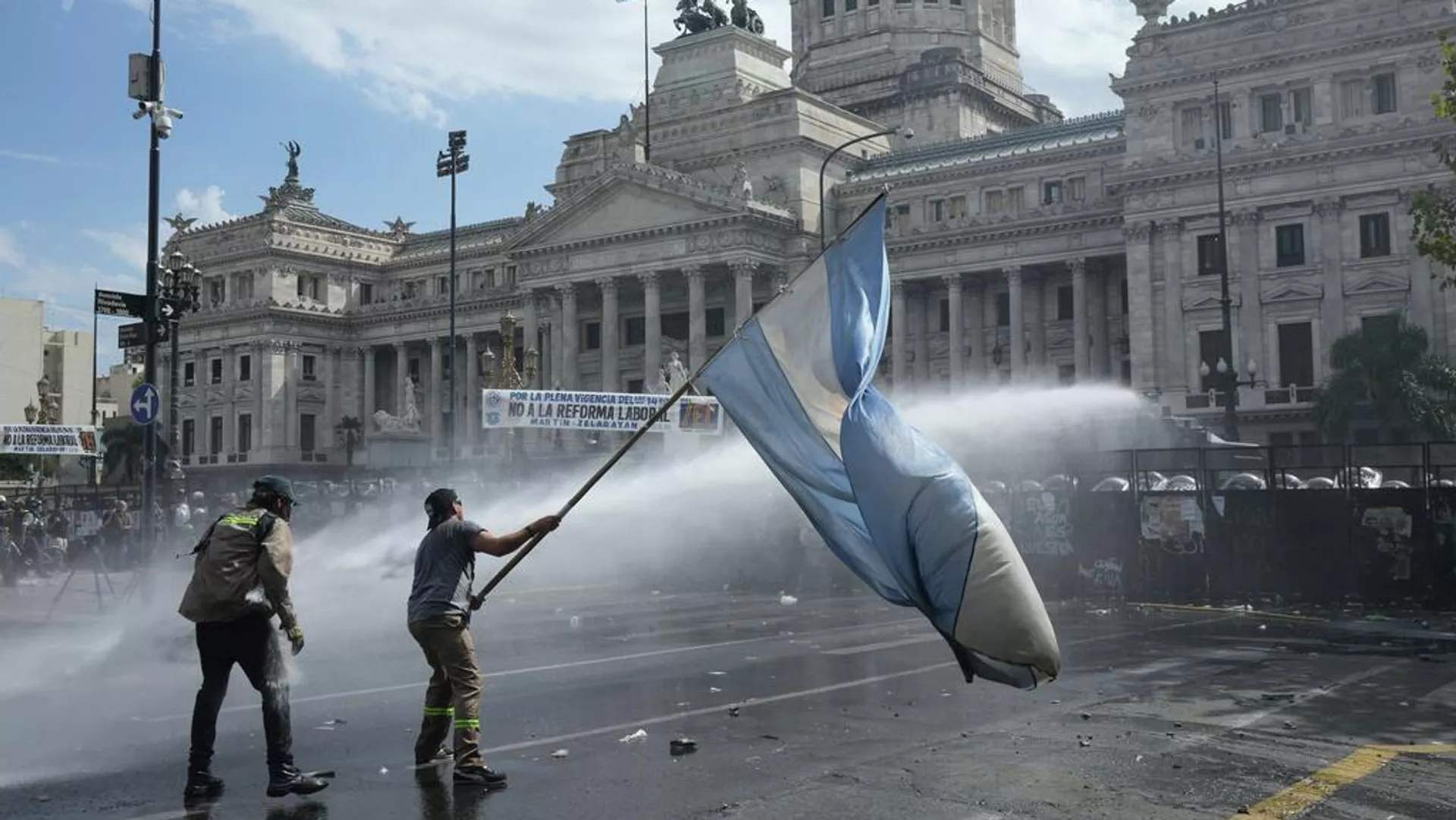 Un manifestante ondea una bandera durante una marcha de sindicatos y simpatizantes de la oposición contra un proyecto de ley de reforma laboral propuesto por el Gobierno del presidente Javier Milei frente al Congreso en Buenos Aires Un manifestante ondea una bandera durante una marcha de sindicatos y simpatizantes de la oposición contra un proyecto de ley de reforma laboral propuesto por el Gobierno del presidente Javier Milei frente al Congreso en Buenos Aires - Sputnik Mundo, 1920, 27.02.2026