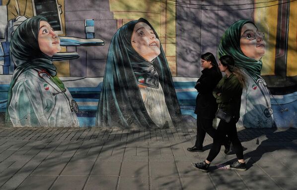 Mujeres caminan junto a un mural en una escuela femenina ubicada en el centro de Teherán, Irán. - Sputnik Mundo