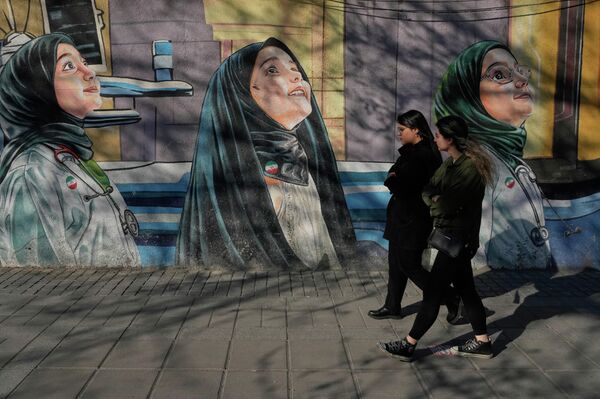 Mujeres caminan junto a un mural en una escuela femenina ubicada en el centro de Teherán, Irán. - Sputnik Mundo