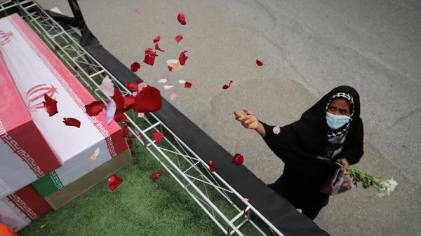 Una mujer arroja pétalos de rosa sobre ataúdes - Sputnik Mundo