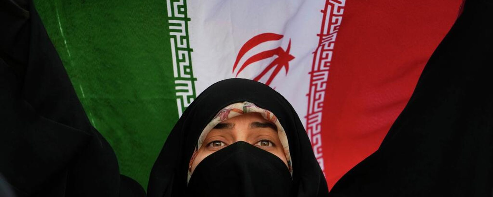 Una mujer iraní sostiene la bandera de su país en una manifestación contra EEUU e Israel en el centro de Teherán - Sputnik Mundo, 1920, 30.08.2026