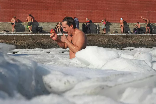 Un hombre se baña en aguas heladas en la ciudad rusa de San Petersburgo, mientras otras personas toman el sol. - Sputnik Mundo