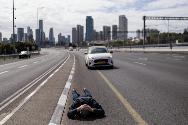 Alerta de un ataque con misiles obligó a un ciudadano israelí de esperar tumbado sobre la carretera como medida de precaución. - Sputnik Mundo
