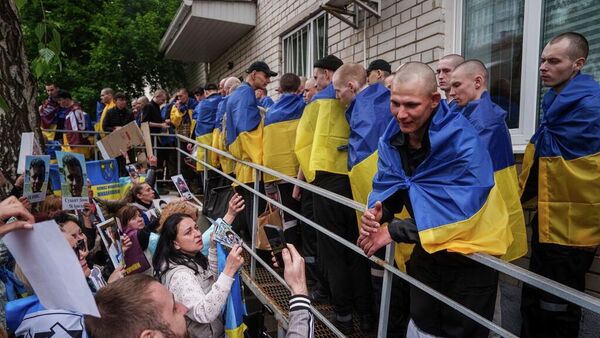 Familiares de soldados ucranianos desaparecidos y encarcelados muestran fotografías a militares devueltos de su cautiverio en un intercambio de prisioneros de guerra en Ucrania, el 6 de mayo de 2025 - Sputnik Mundo