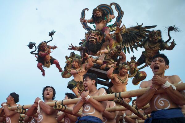 Participantes de una tradicional procesión en Indonesia portan figurillas que representan a los espíritus malignos para su posterior purificación. - Sputnik Mundo