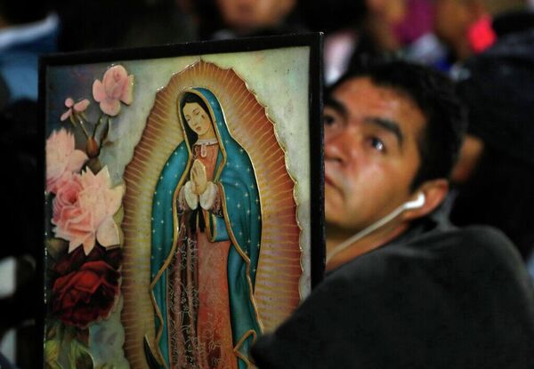 Un mexicano sostiene una imagen de la Virgen de Guadalupe - Sputnik Mundo