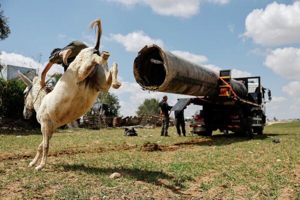 Un menor beduino monta en burro mientras unos trabajadores cargan parte de un misil caído en un vehículo policial, en medio del conflicto entre Estados Unidos e Israel contra Irán, cerca de Zaarura, una aldea beduina no reconocida situada en el sur de Israel. - Sputnik Mundo