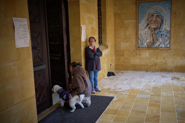 Una mujer católica se arrodilla junto a su perro a la entrada de una iglesia durante la misa del Domingo de Ramos en Beirut, el Líbano. - Sputnik Mundo