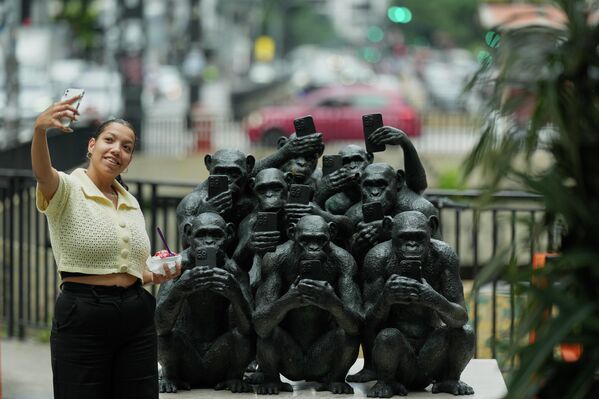 Una mujer se toma una fotografía junto a una escultura titulada Desconectados, del artista brasileño Beto Gatti en Sao Paulo. - Sputnik Mundo