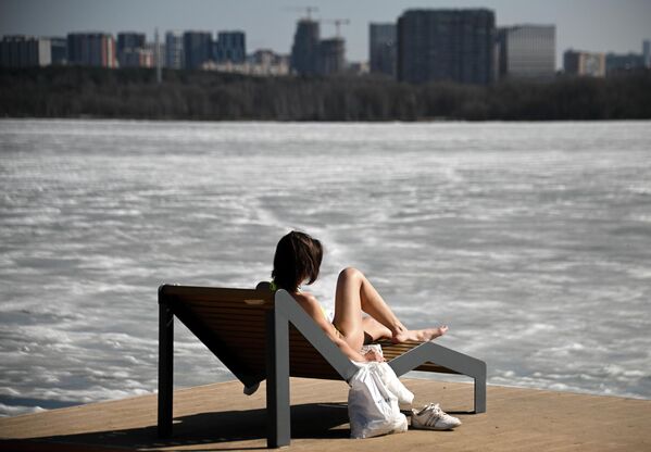 Una chica toma el sol junto a un río que aún no se ha descongelado en un parque de Moscú, Rusia. - Sputnik Mundo