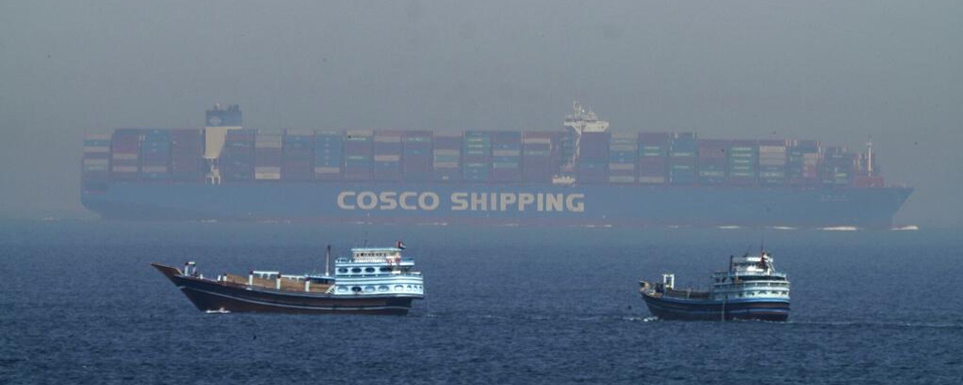 Dos dhows tradicionales navegan junto a un gran buque portacontenedores en el estrecho de Ormuz, 19 de mayo de 2023 - Sputnik Mundo, 1920, 07.04.2026