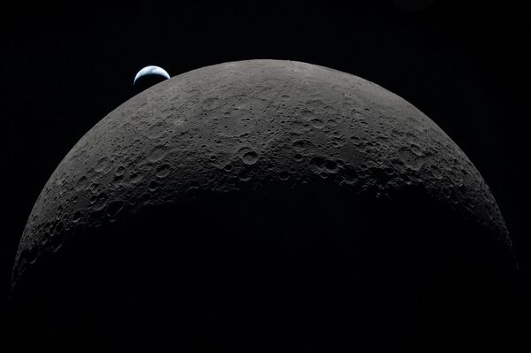 Vista de la Tierra parcialmente oculta por la Luna, fotografiada a través de la ventanilla de la nave espacial Orion durante el sobrevuelo lunar de la tripulación de la misión Artemis II. - Sputnik Mundo